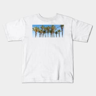 Row of tropical feeling palm trees against blue sky with luch green fronds. Kids T-Shirt